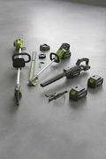 A matched set of cordless landscaping power tools with batteries arranged on a workshop floor